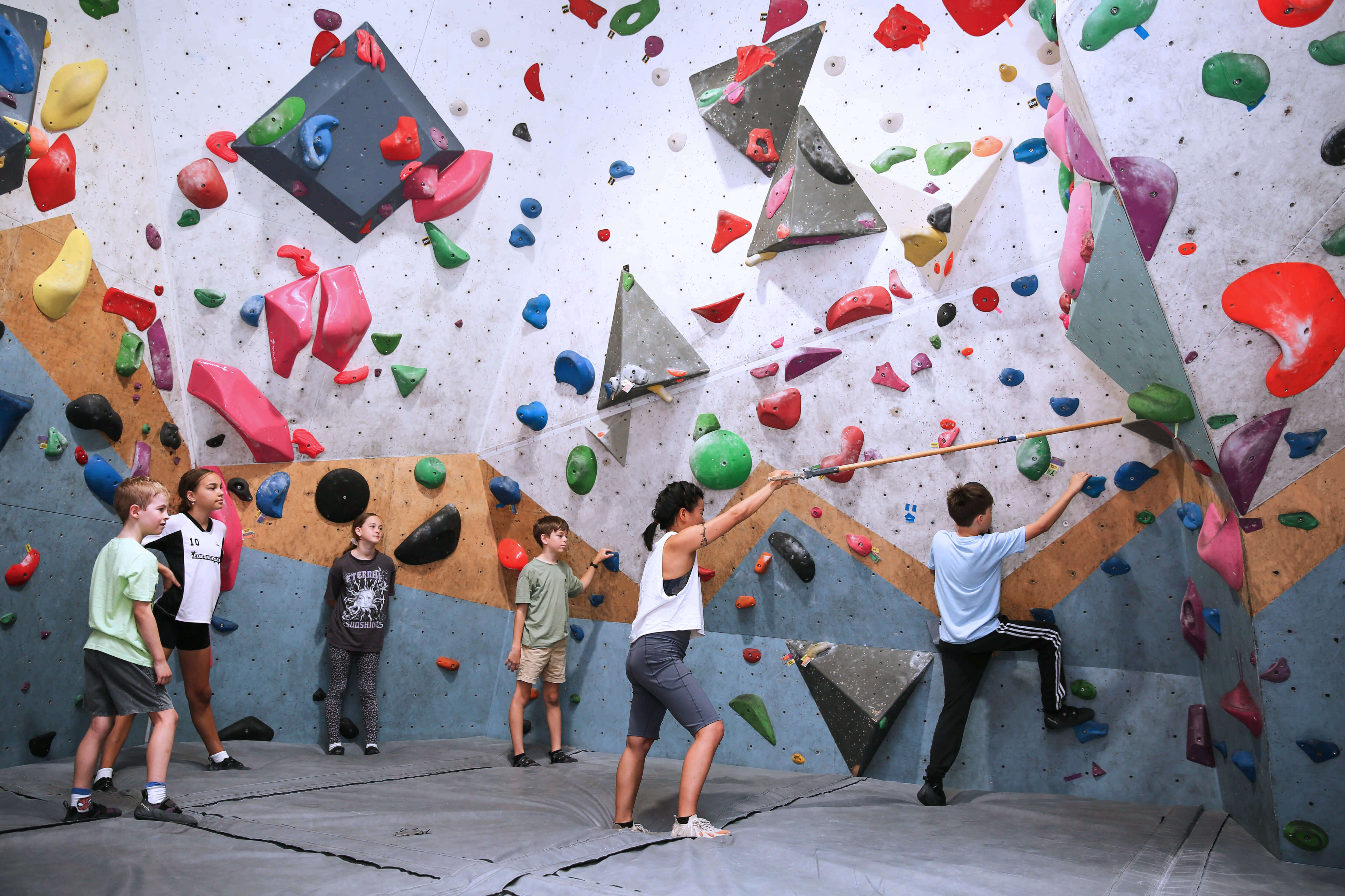 Wall Walkers coach helping students on a bouldering wall